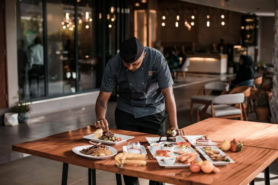 Cuisinier dressant plusieurs assiettes sur une table de restaurant